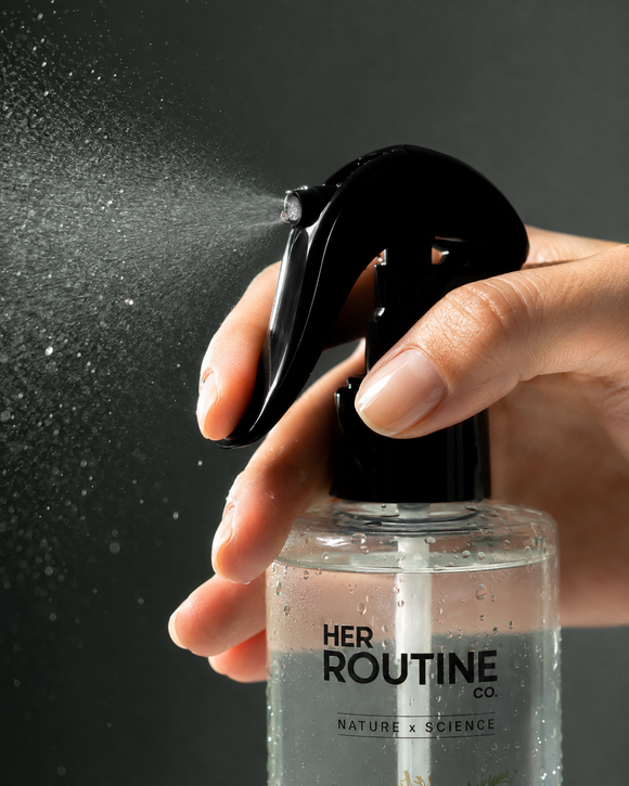 Woman applying HER ROUTINE CO. spray along her scalp part after showering